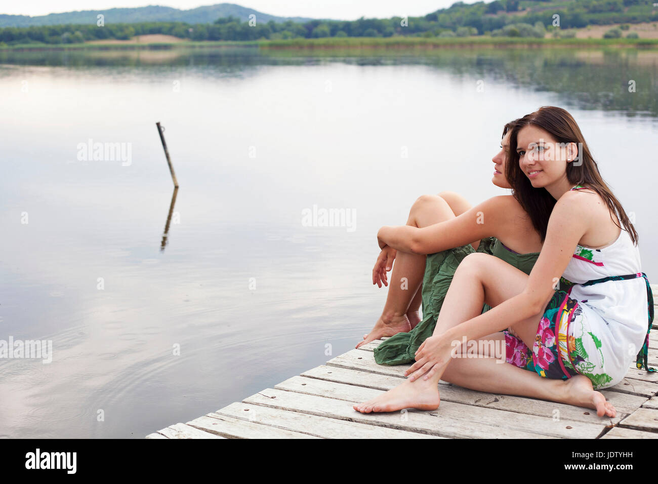 Women sitting together on pier Stock Photo