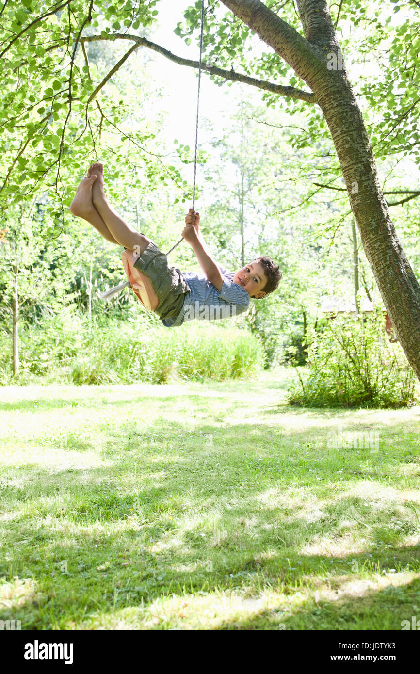 Boy swinging from tree outdoors Stock Photo Alamy