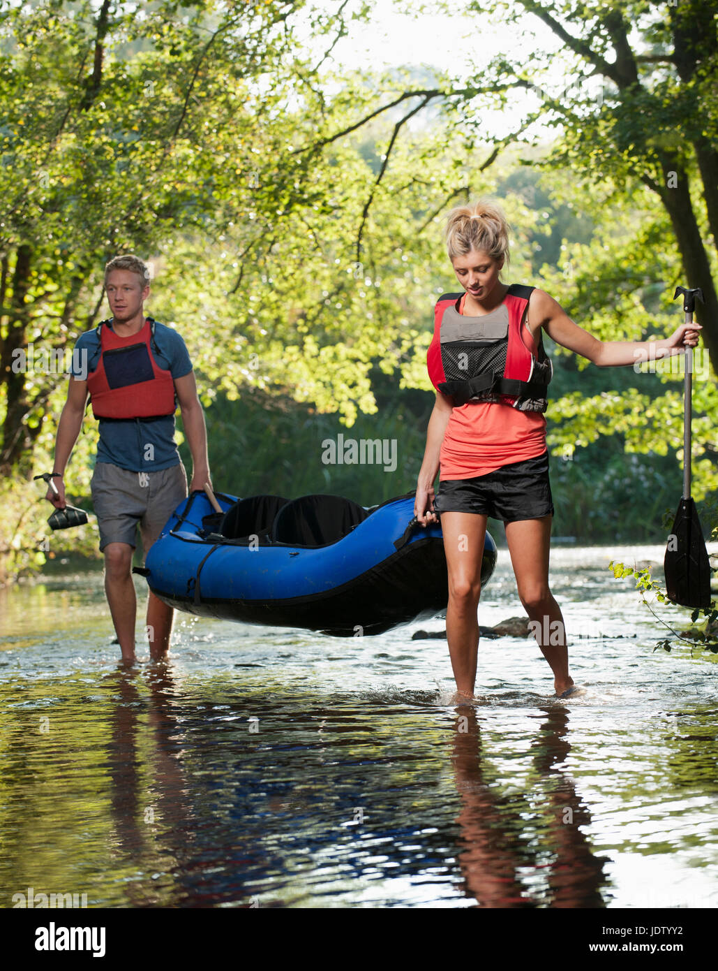 Couple carrying kayak in creek Stock Photo Alamy