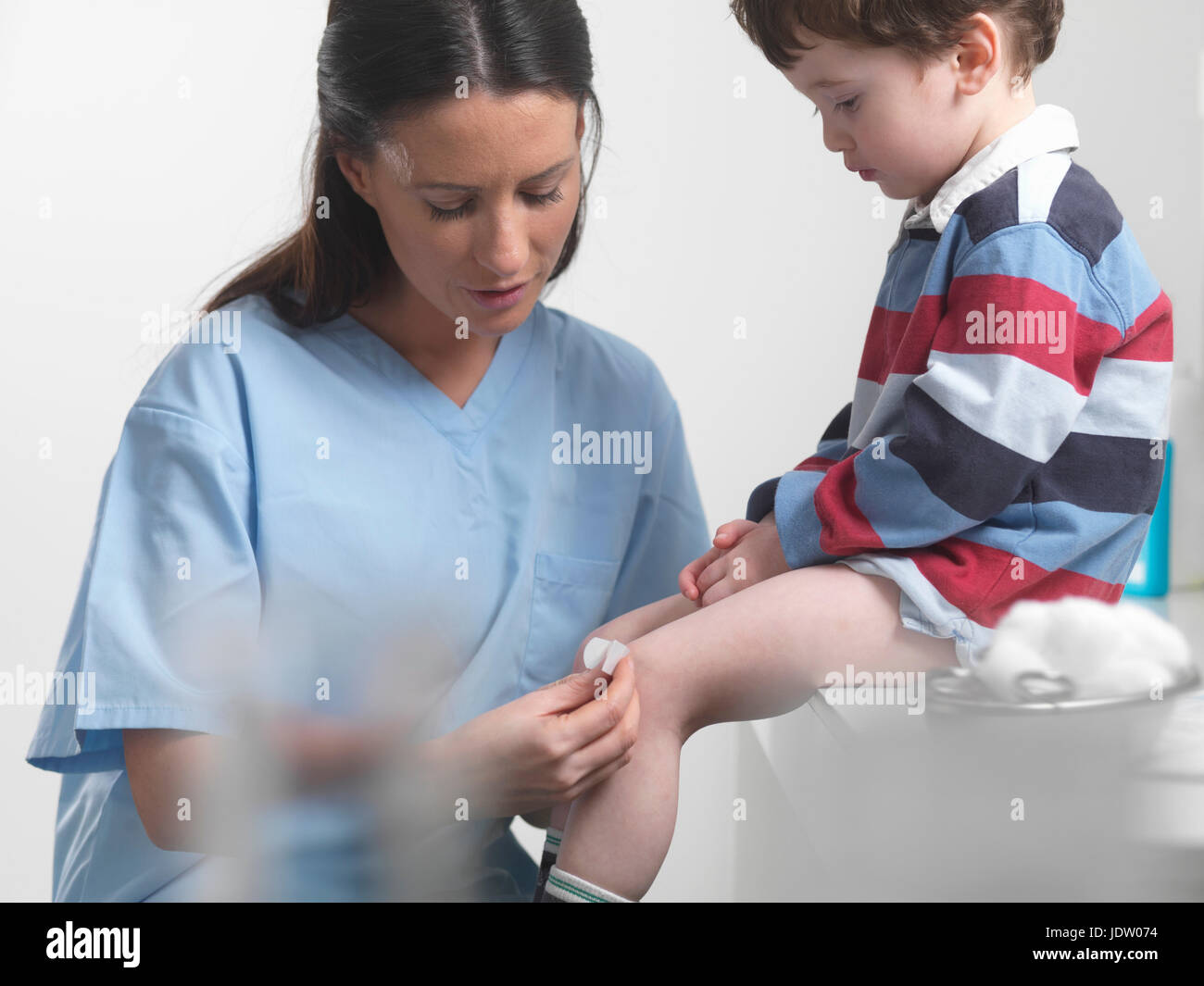 Nurse applying bandage to boys knee Stock Photo