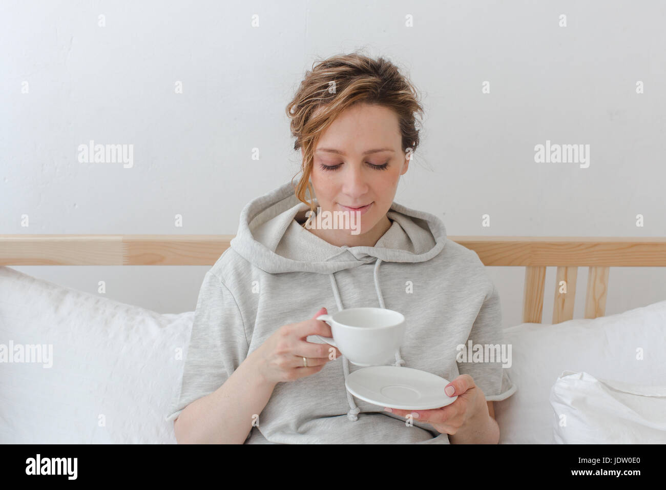 Female having breakfast sitting in bed Stock Photo