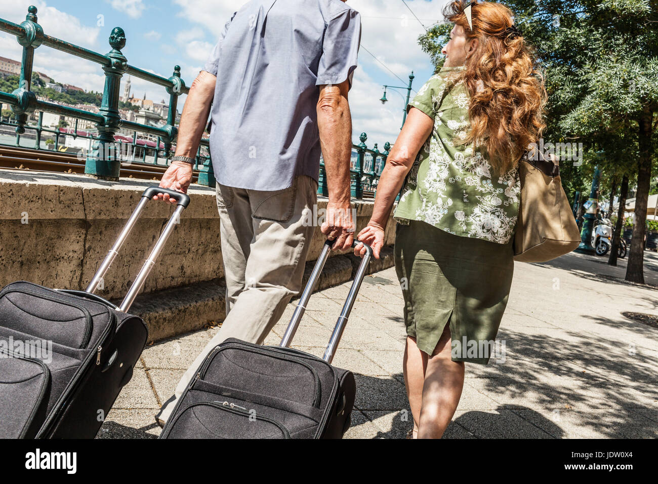 Older couple rolling luggage on street Stock Photo