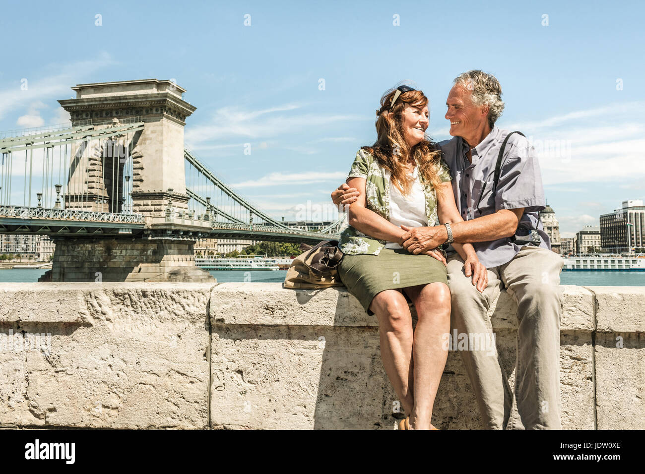 Older couple sitting on bridge Stock Photo
