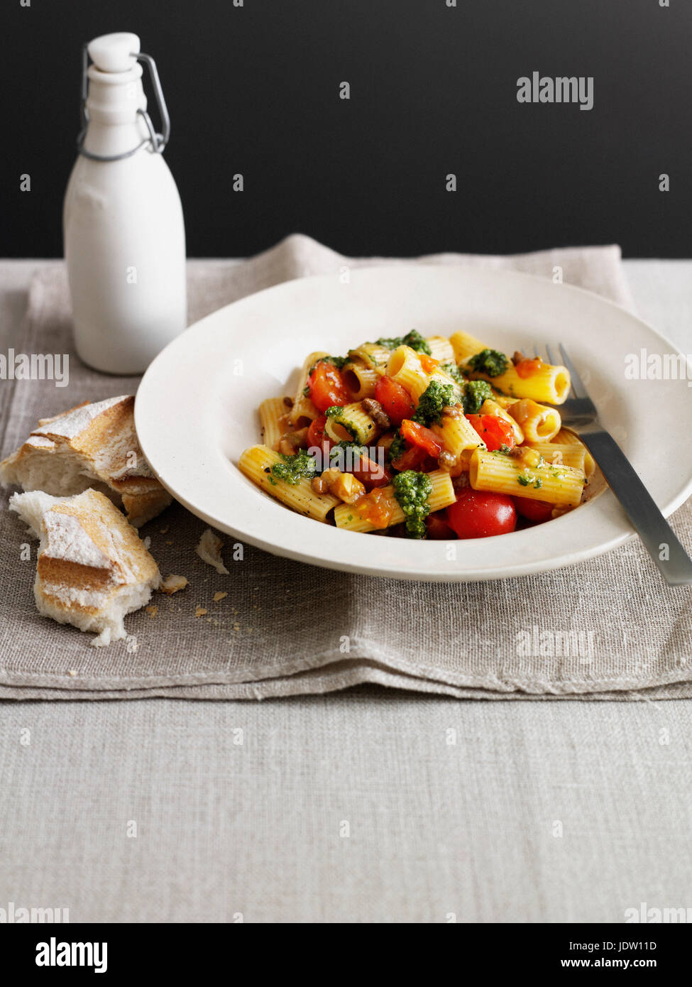 Bowl of pasta with tomatoes and bread Stock Photo