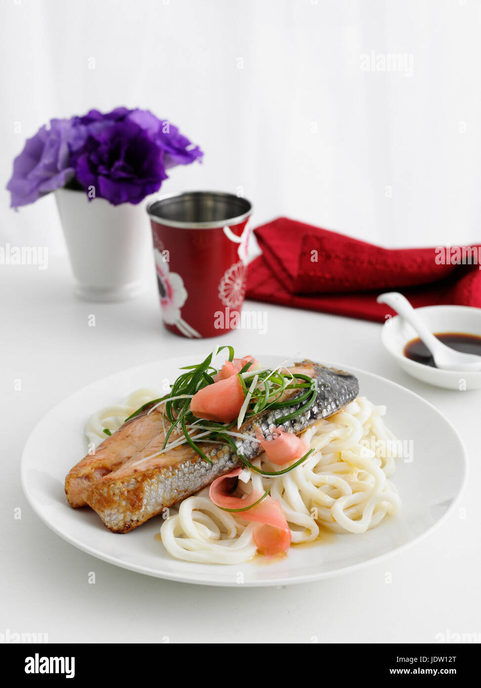 Plate of fish and pasta on table Stock Photo