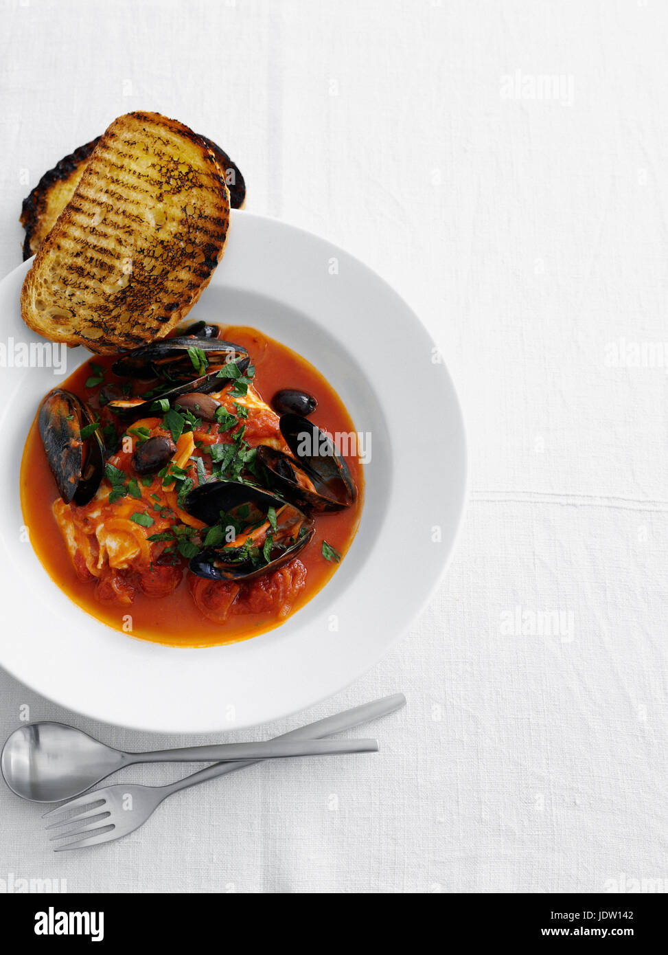 Bowl of mussels in soup with bread Stock Photo