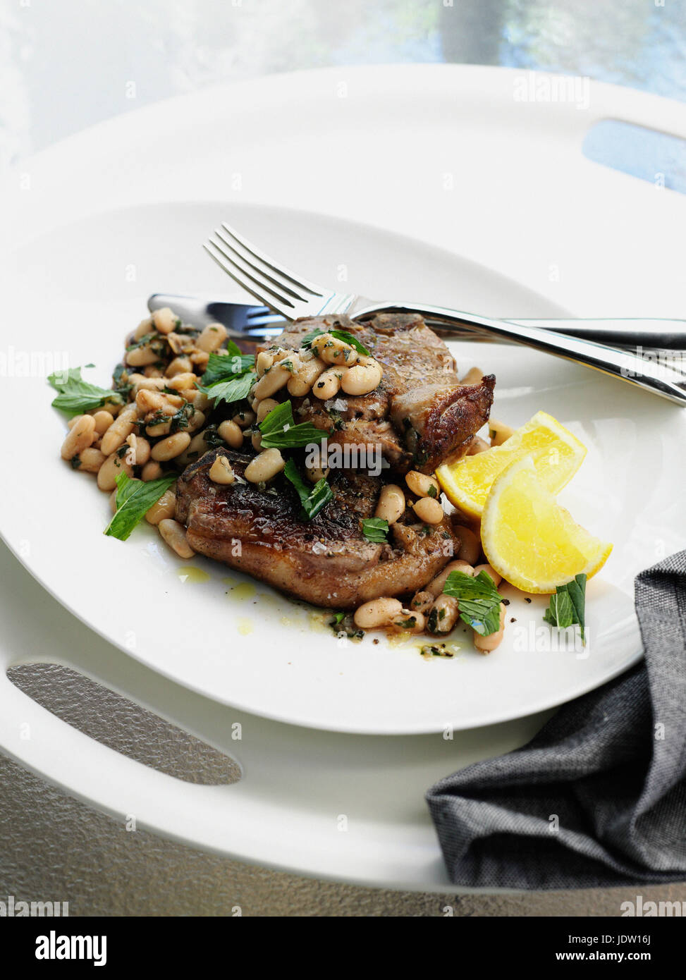 Plate of meat with beans and lemon Stock Photo