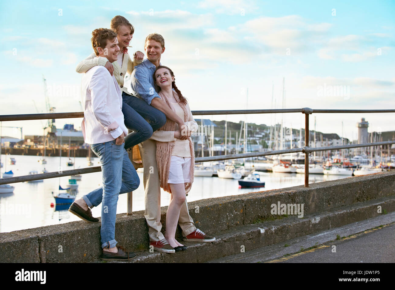 Couples standing by railing of harbor Stock Photo