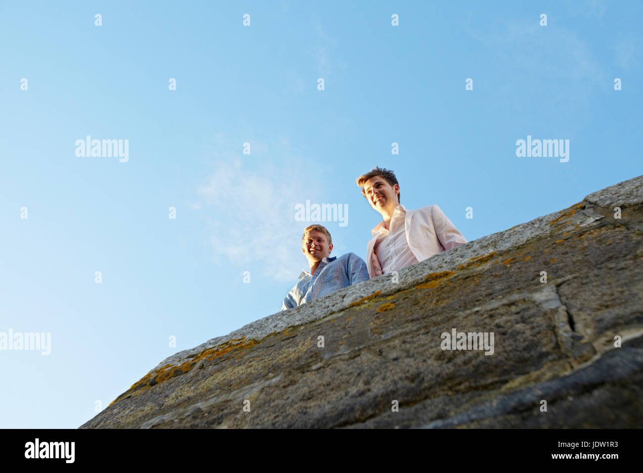Men looking over edge of stone wall Stock Photo
