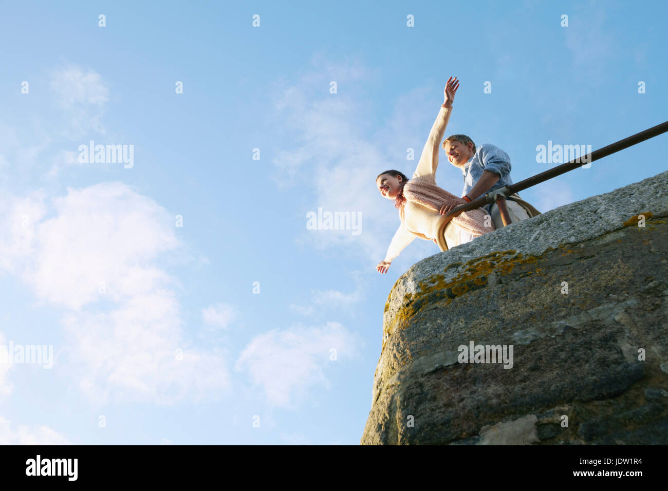 Couple playing on edge of stone wall Stock Photo