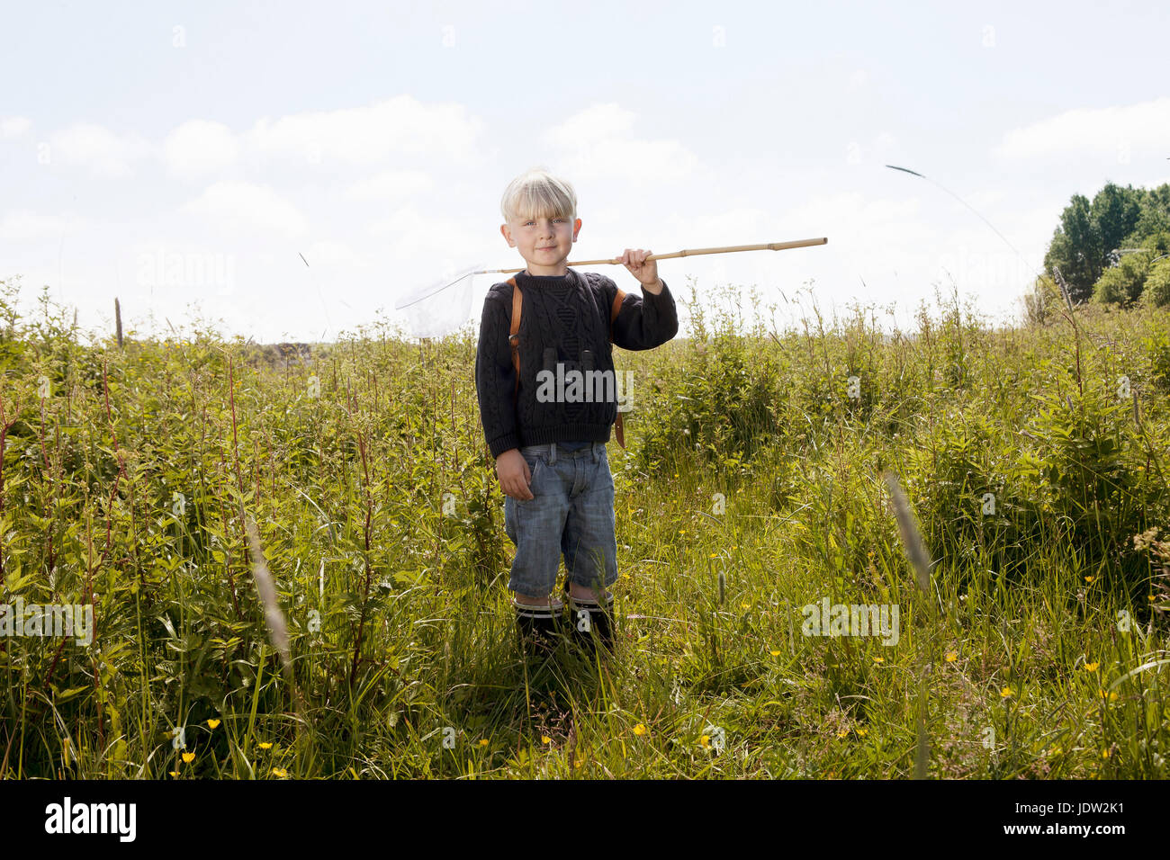 Boy walking in field of tall grass Stock Photo