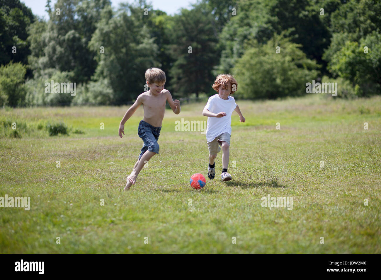 Children playing soccer in grassy field Stock Photo