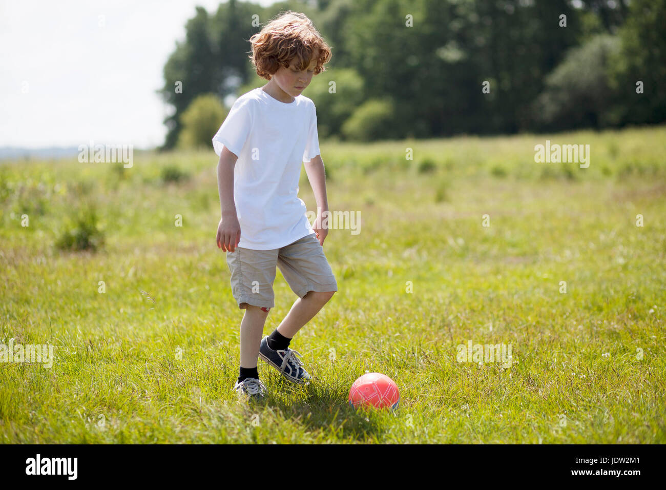Girl kicking soccer ball in grassy field Stock Photo