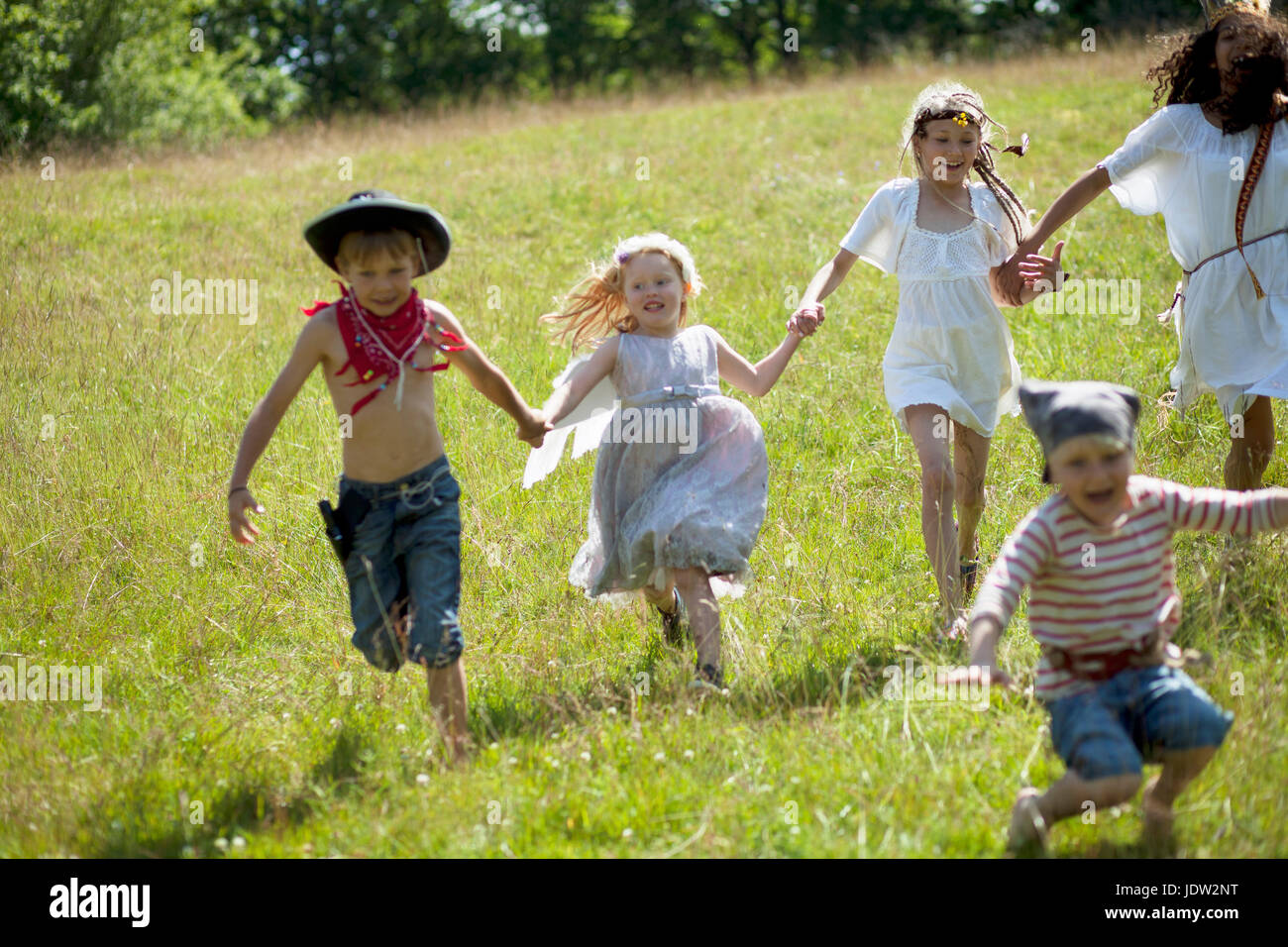 Children in costumes running in field Stock Photo