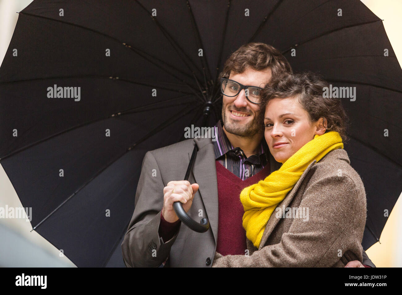 Couple under umbrella on city street Stock Photo