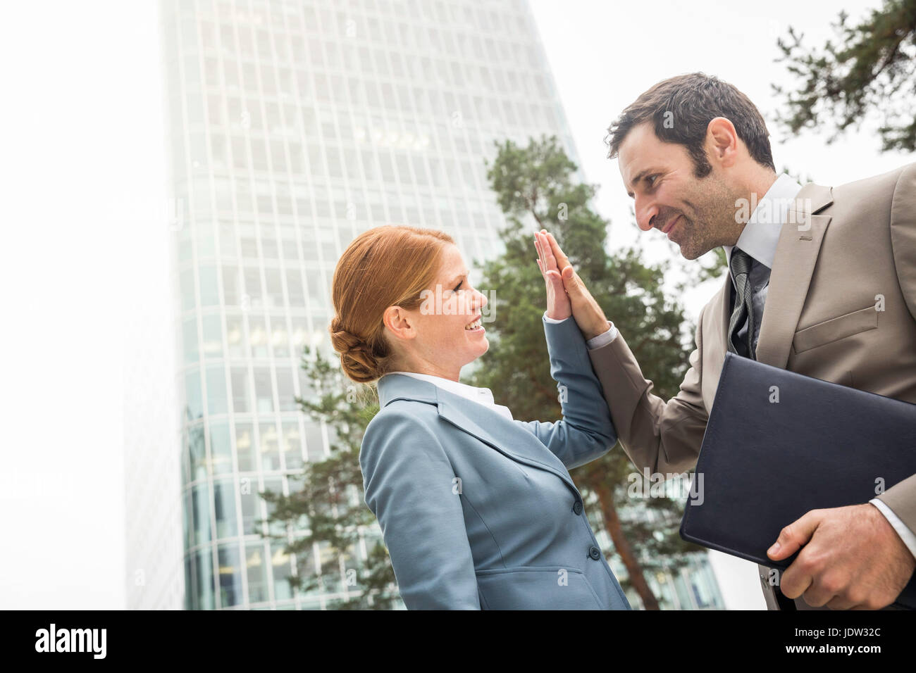 Business people high fiving outdoors Stock Photo