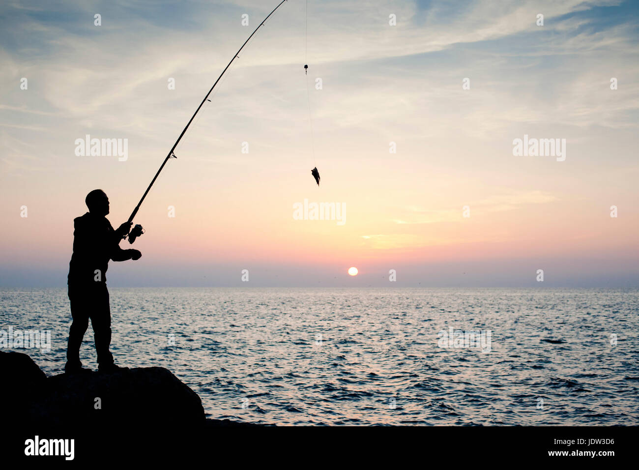Silhouette of man fishing at sunset Stock Photo - Alamy