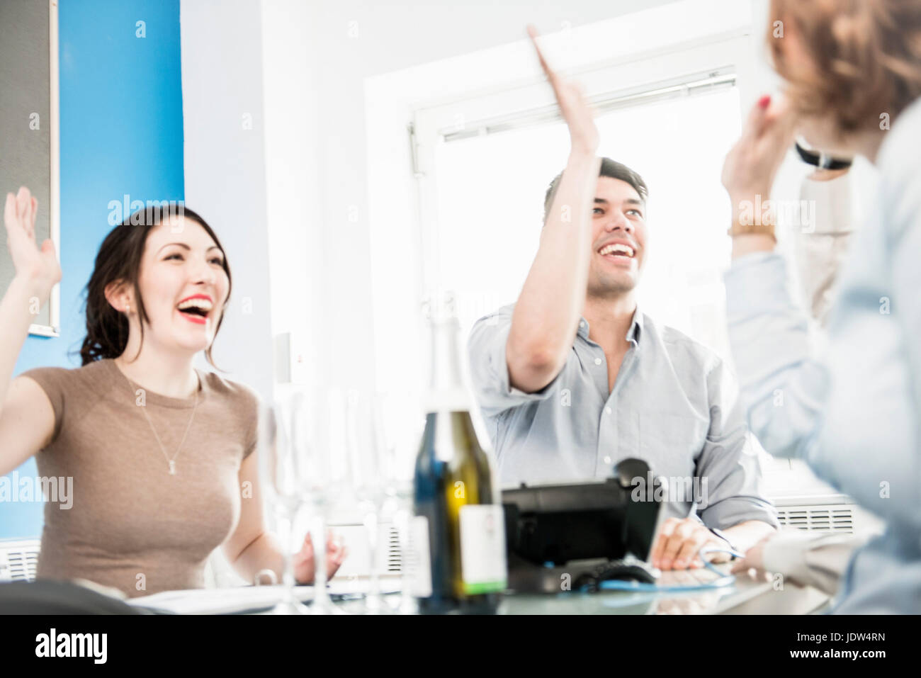 Colleagues giving high fives in office, champagne on table Stock Photo
