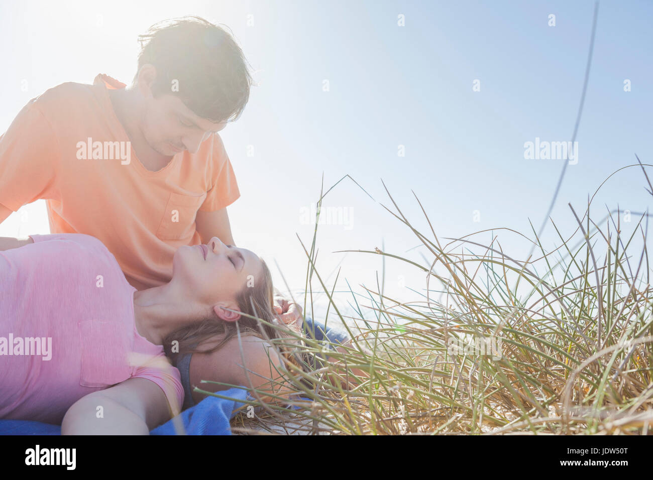 Couple sitting in grass, woman's head on man's lap Stock Photo