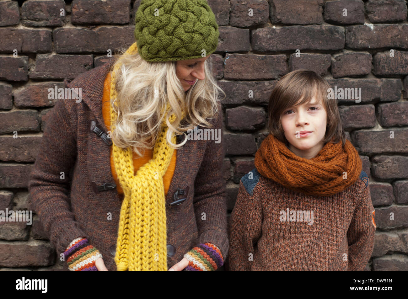 Mother and son standing against brick wall, portrait Stock Photo