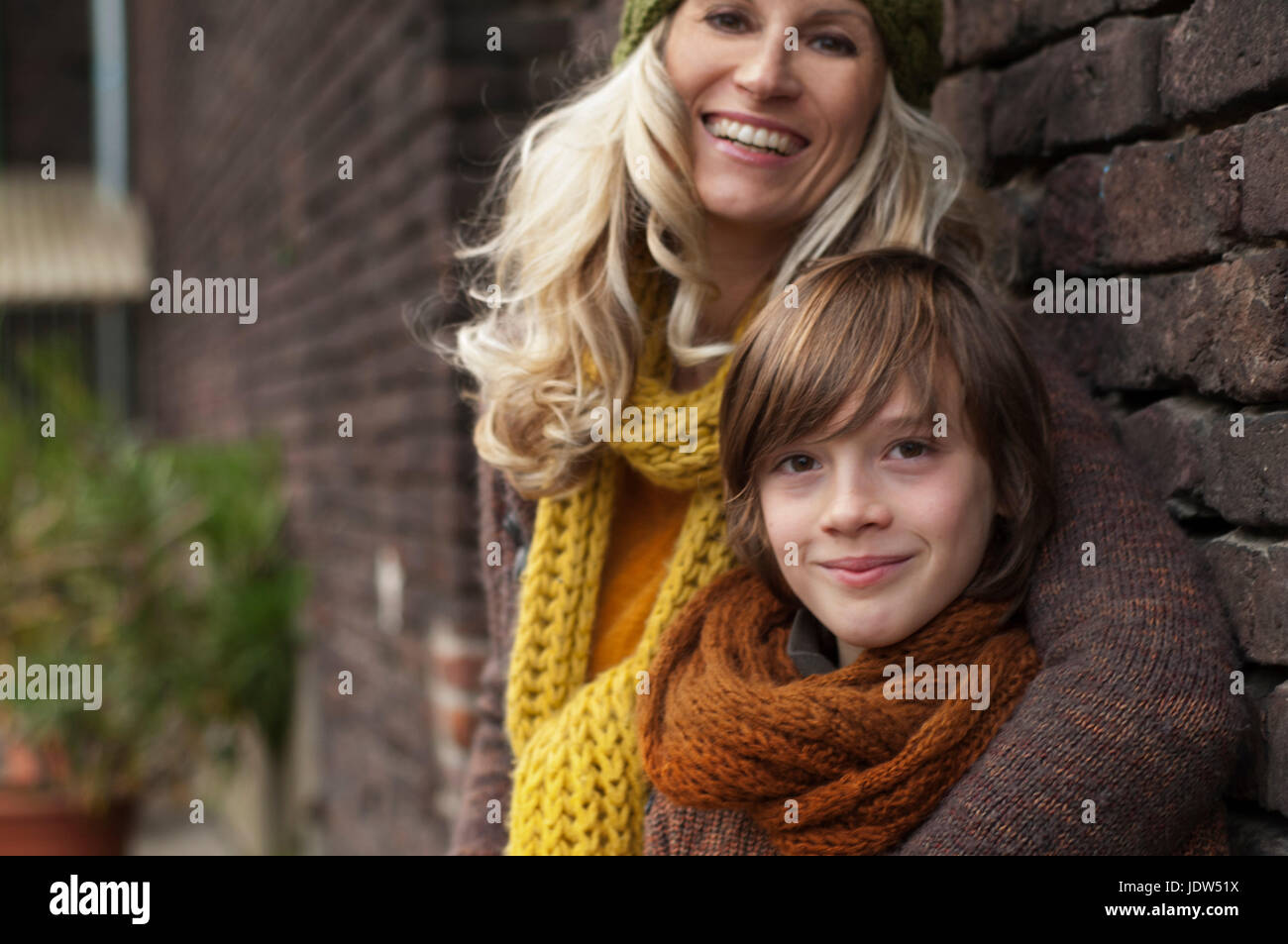 Mother and son smiling against brick wall, portrait Stock Photo