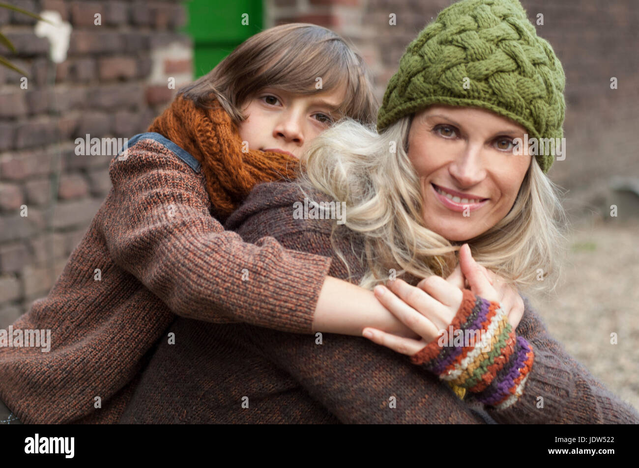 Boy embracing mother outdoors, smiling Stock Photo