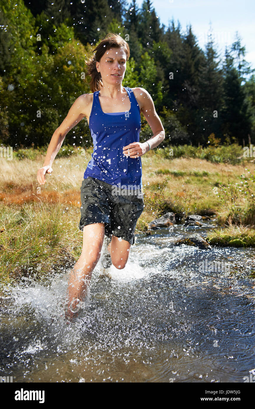 Woman running through river, Chamonix, Haute Savoie, France Stock Photo