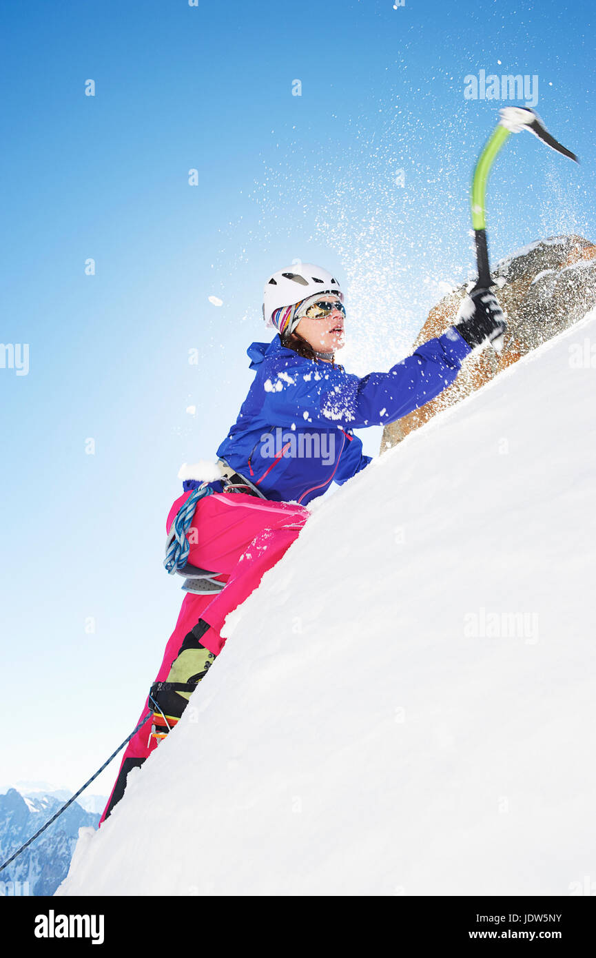 Female mountain climber using ice pick Stock Photo