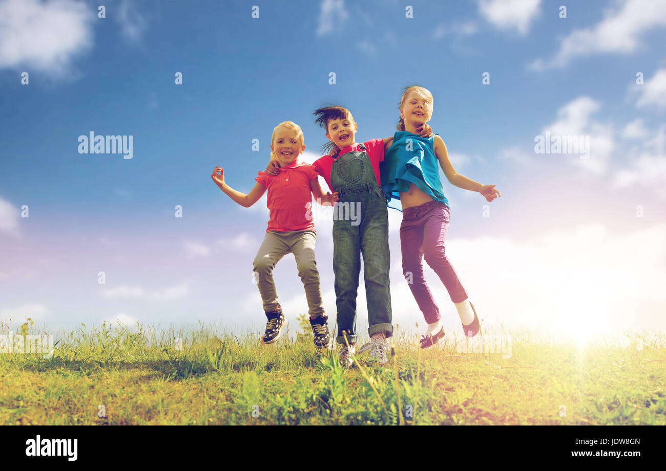 group of happy kids jumping high on green field Stock Photo