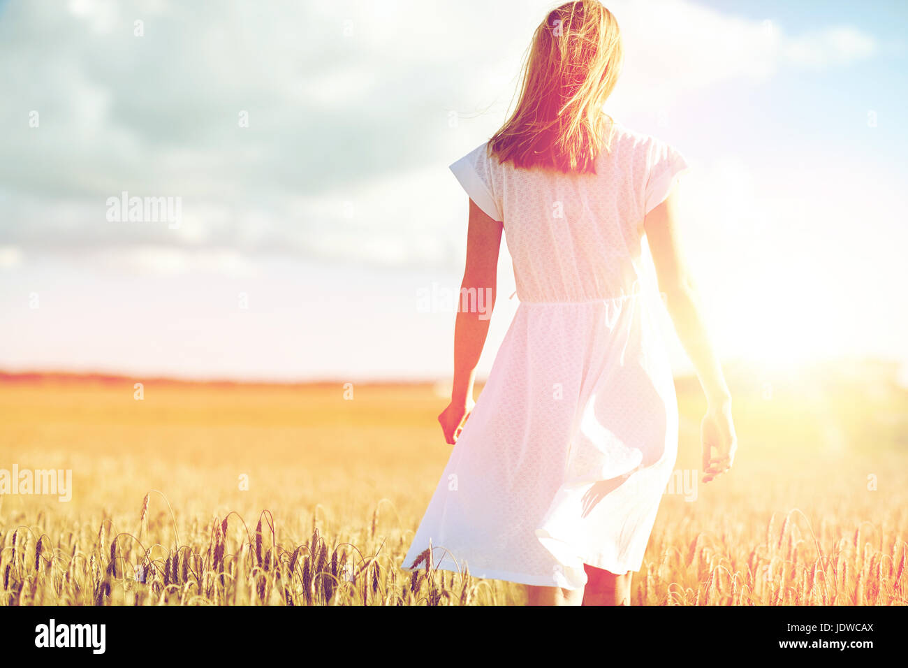 young woman in white dress walking along on field Stock Photo - Alamy