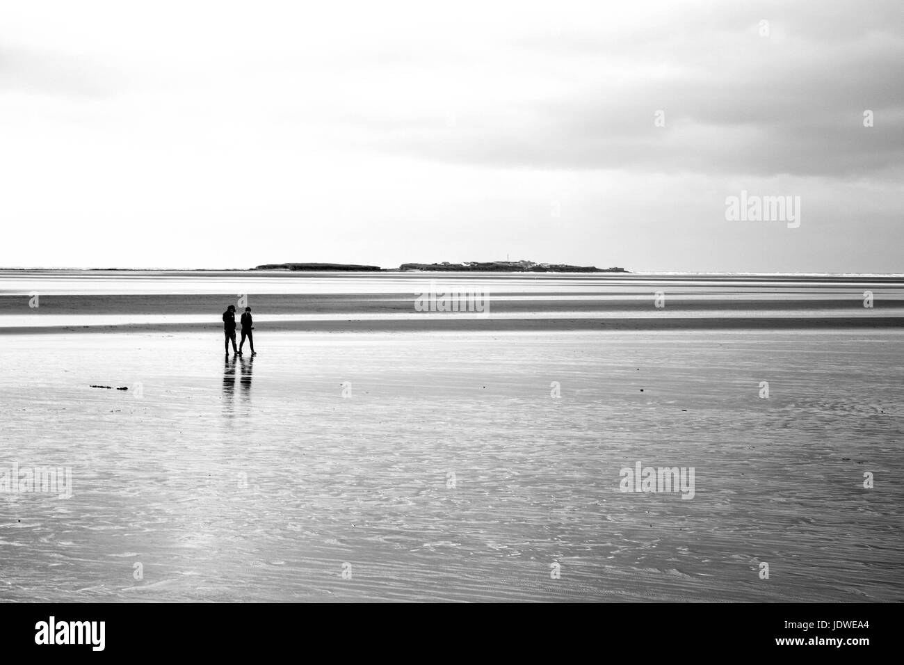 Couple walking out to Hilbre Island Stock Photo