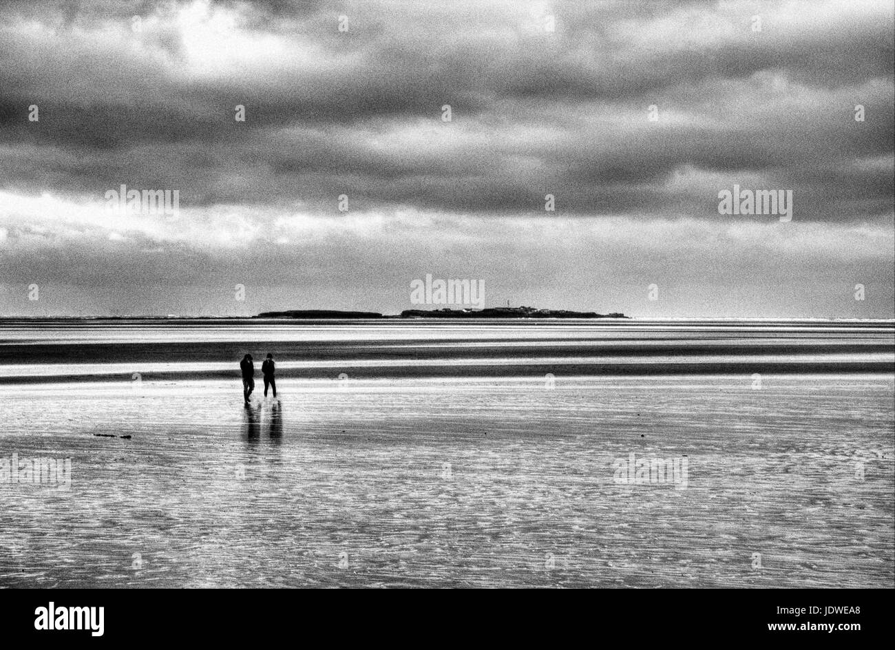 Couple walking out to Hilbre Island Stock Photo