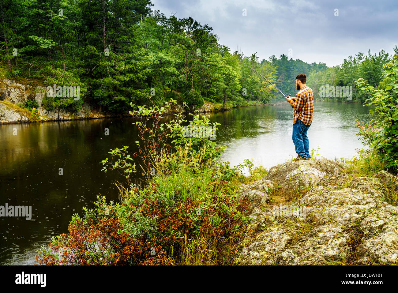Upper Peninsula, Michigan, August 11, 2016: a dedicated angler is fishing on a river near Marquette, Michigan Stock Photo
