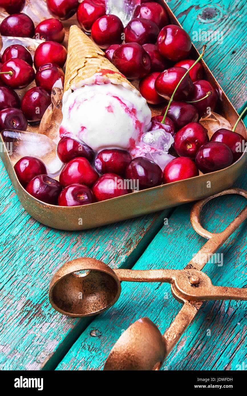 vanilla ice cream in waffle cones and cherry on rustic wooden table Stock Photo