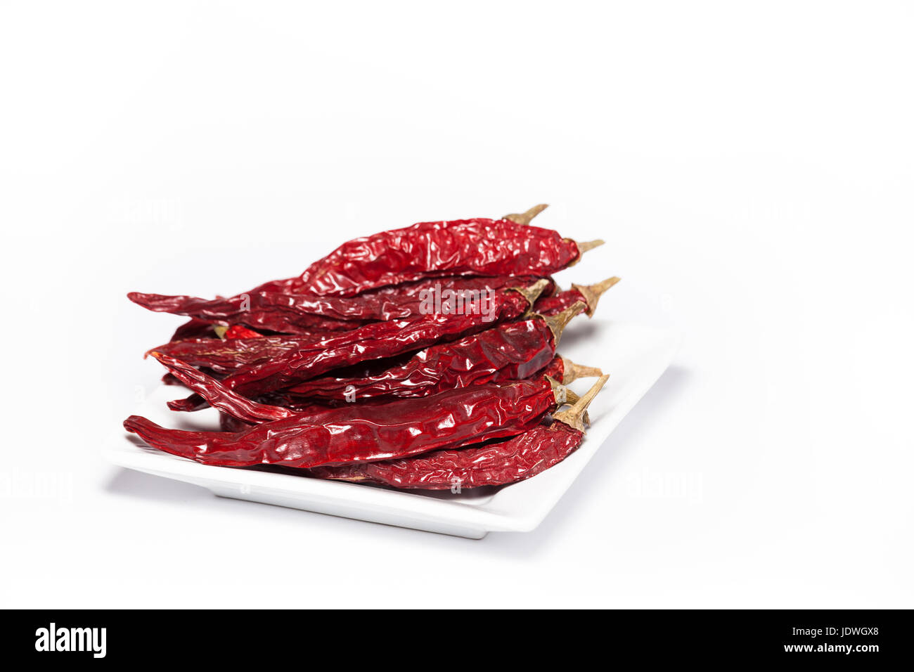Food photography photo of dried red chilies on a plate isolated on white background. Beautiful heap of organic red chilies with copy space Stock Photo
