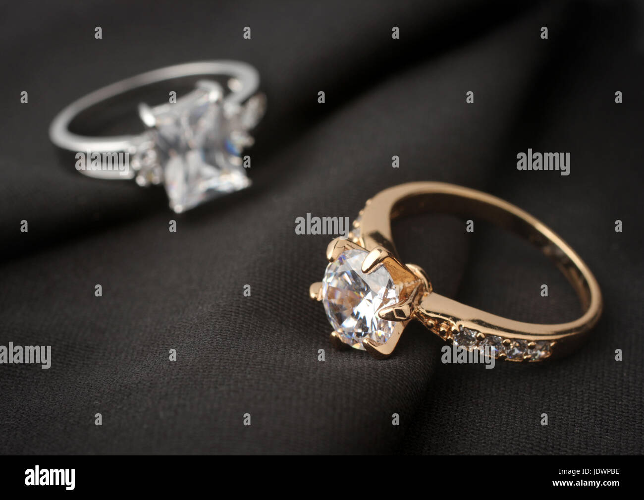 two jewelry rings with diamonds on black cloth Stock Photo - Alamy