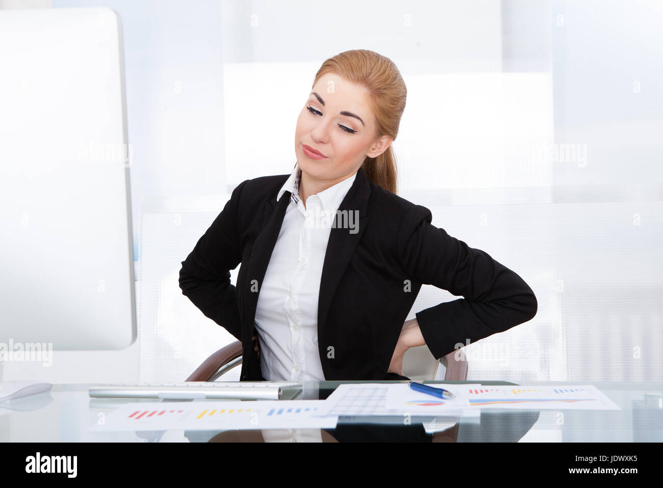 Young Businesswoman Having Back Pain While Sitting At Office Desk Stock ...