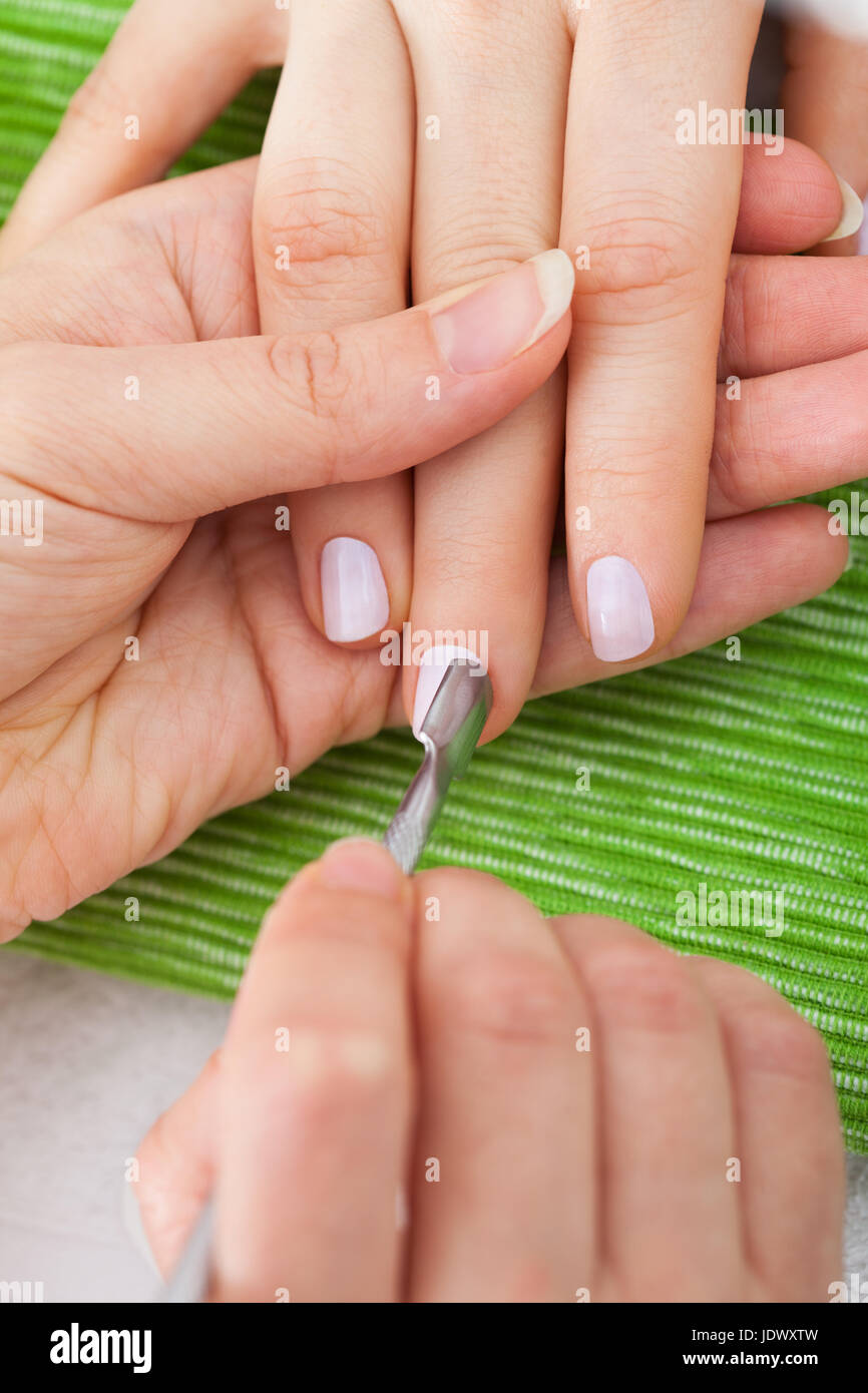 Closeup Of Beautician Hand Giving Manicure Treatment To Woman's Nails
