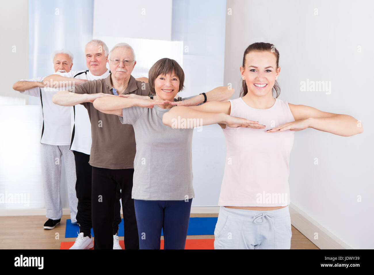 Portrait of happy trainer and senior customers exercising at gym Stock ...