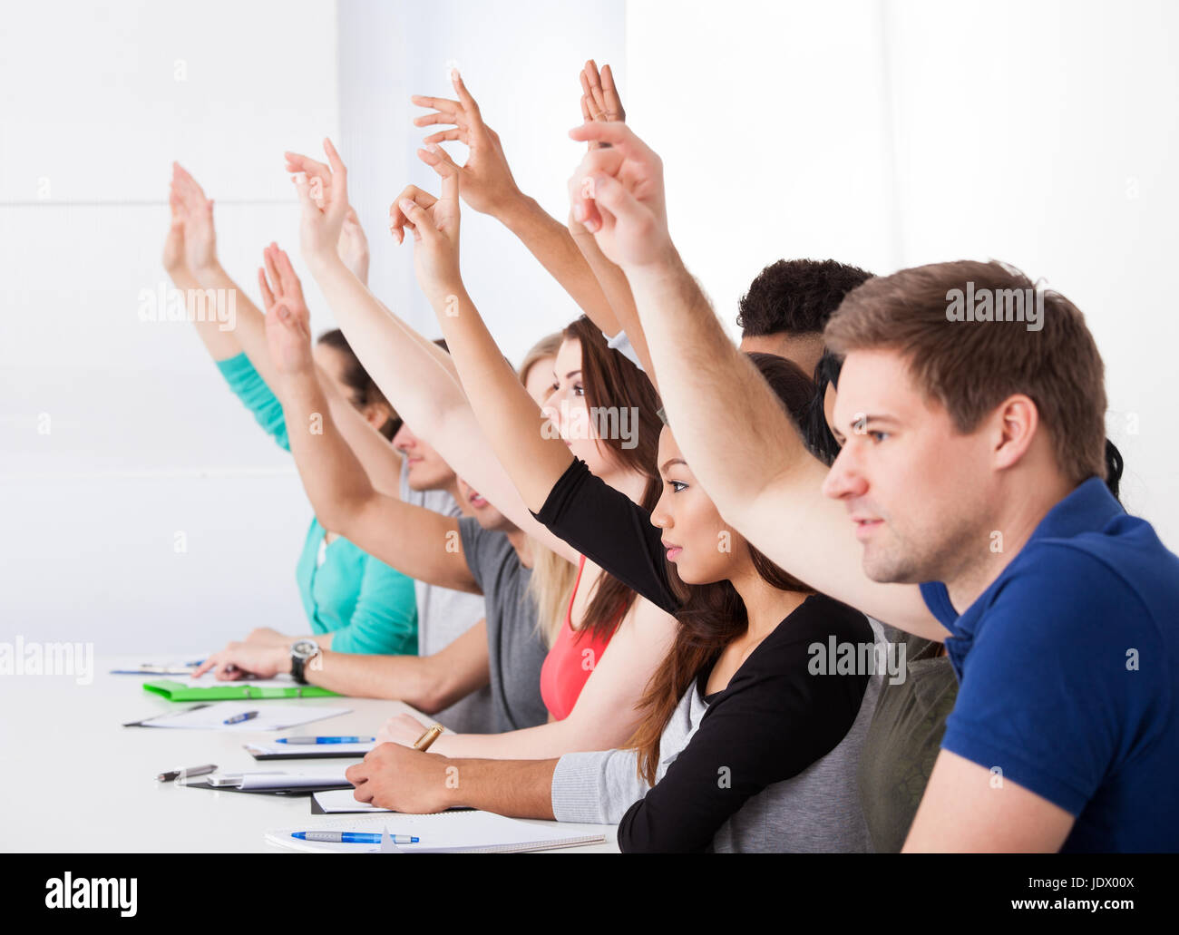 занятия в аудитории. радостный школьник с расставленными руками. студентка и педагог. урок ребята поднимают руку. девочка поднимает руку на уроке.