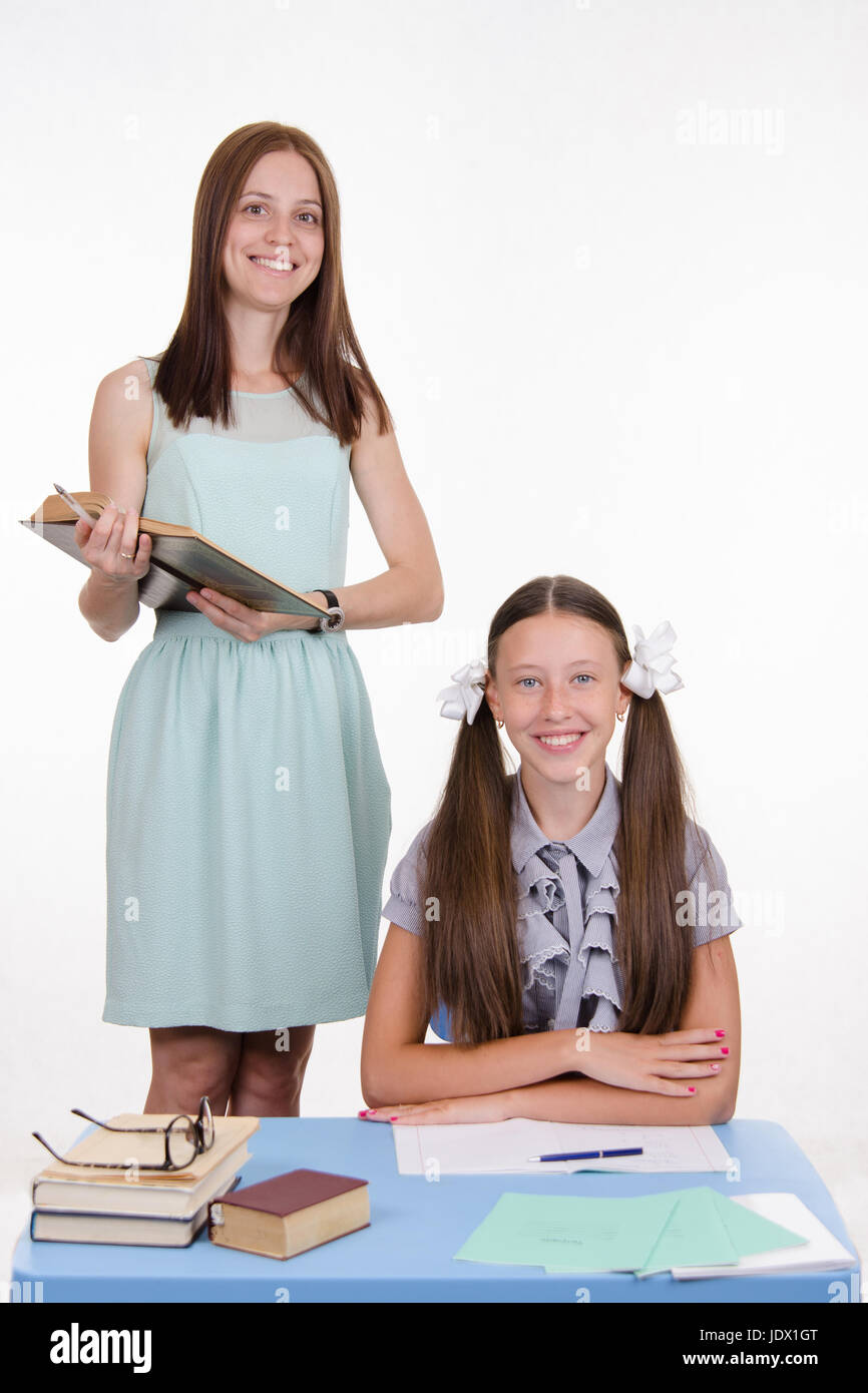 Teacher standing at desk behind which sits a diligent student Stock ...