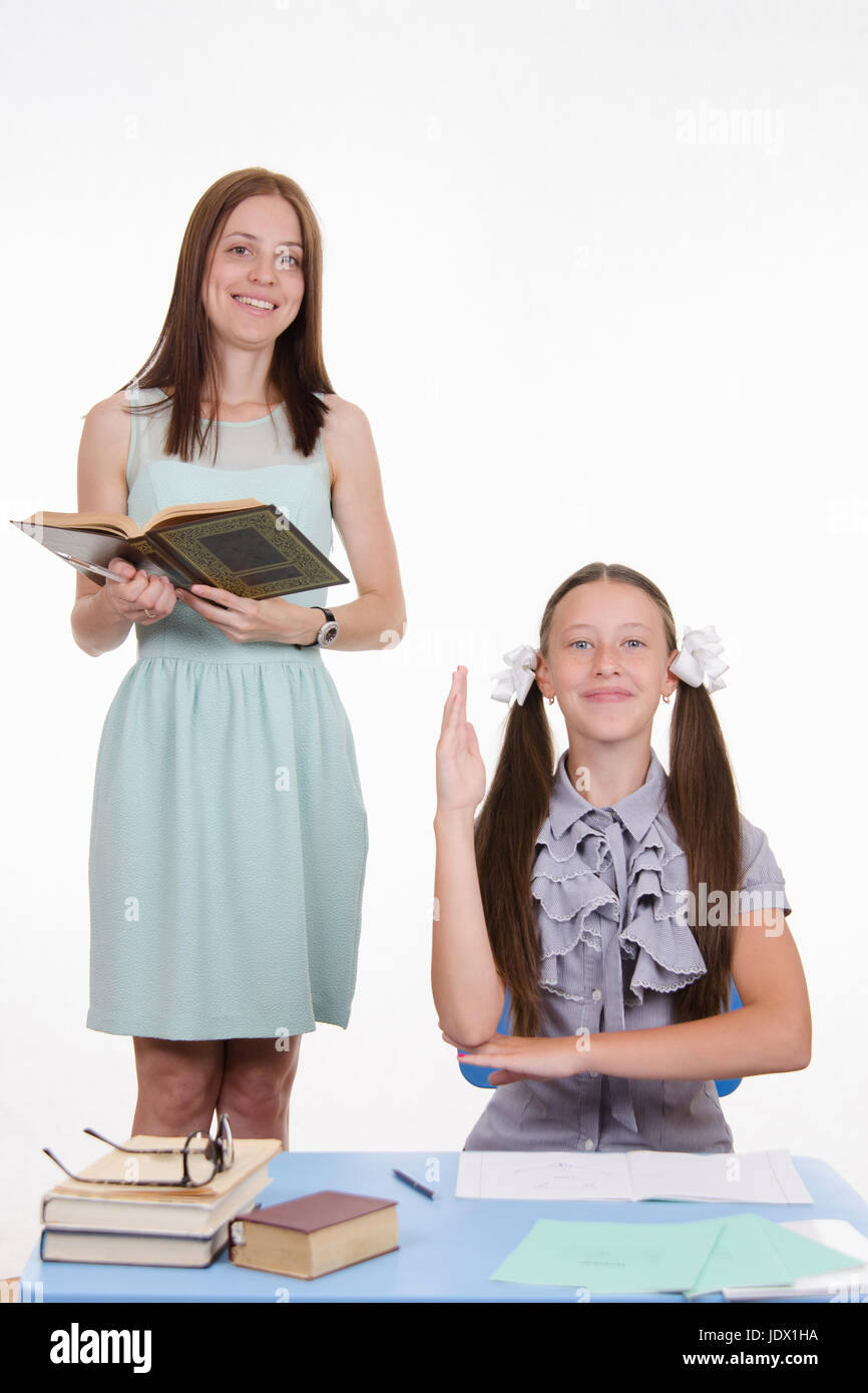 Teacher standing at desk behind which sits a diligent student Stock ...