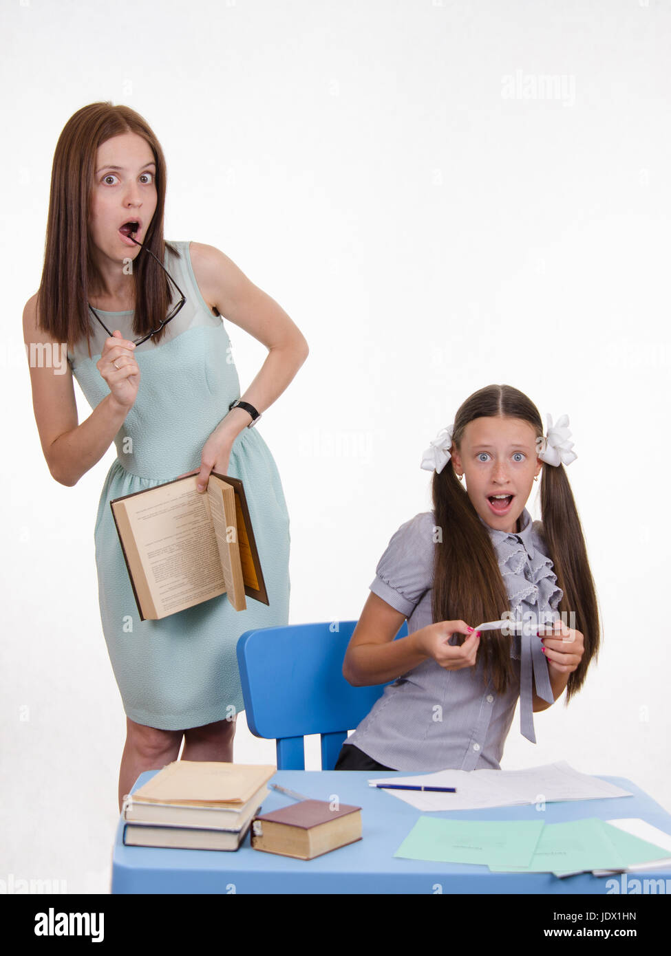 Teacher standing at desk behind which sits a pupil is deducted from the ...