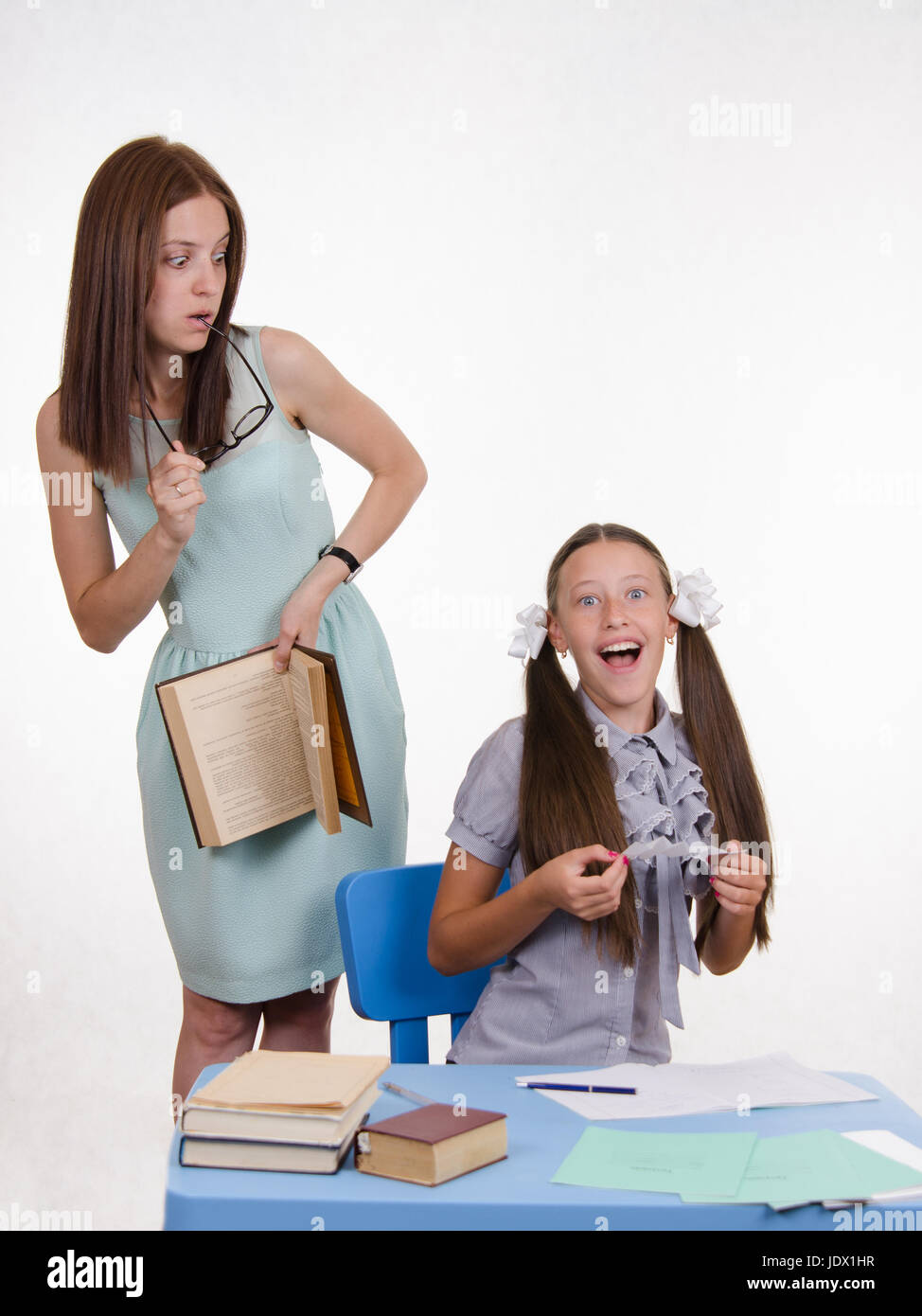 Teacher standing at desk behind which sits a pupil is deducted from the ...