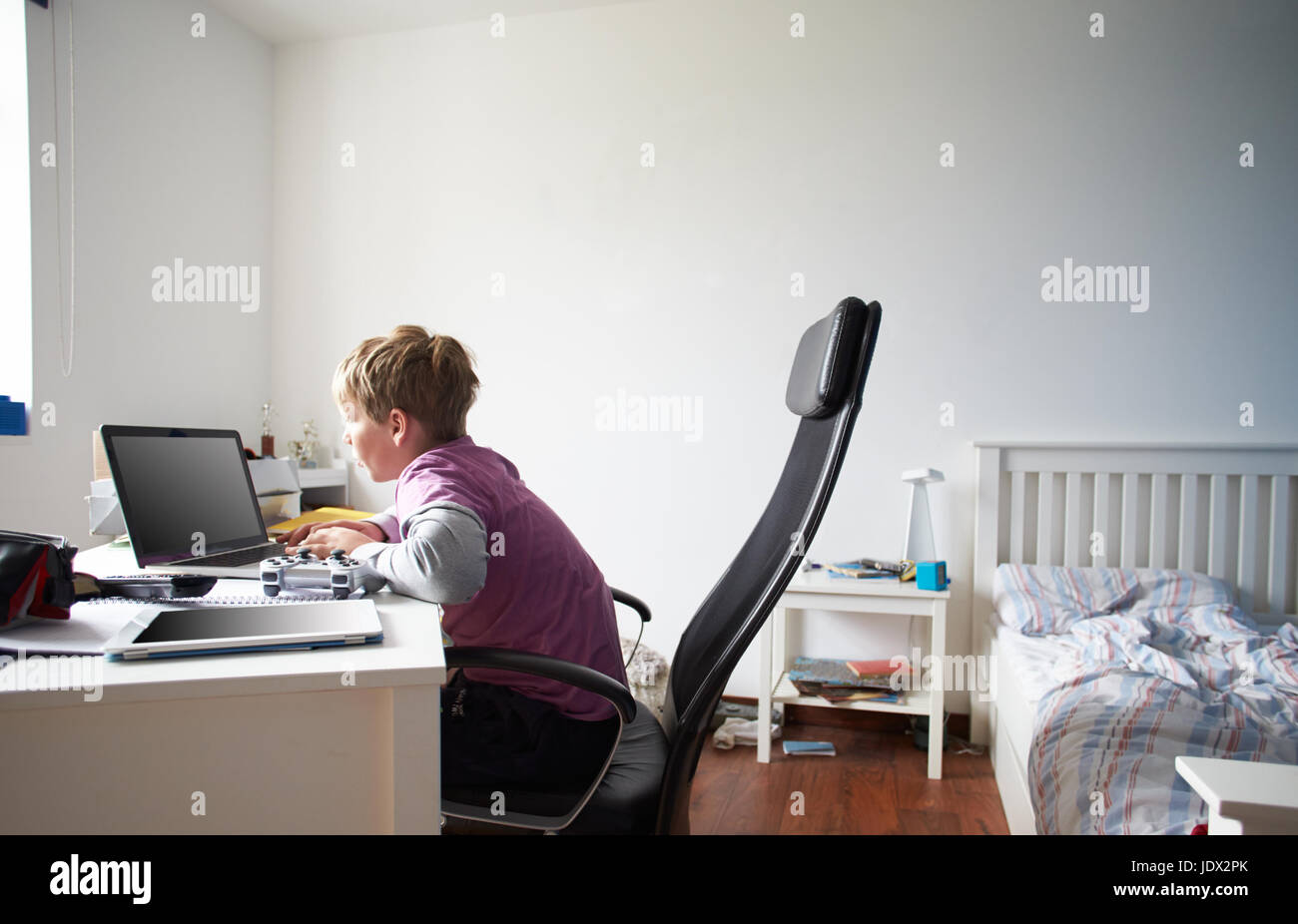Boy Using Laptop In Bedroom Stock Photo - Alamy