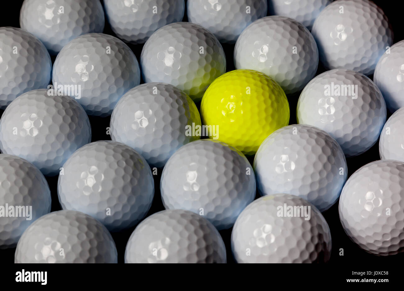 Golf balls. Single yellow ball mixed within many white balls