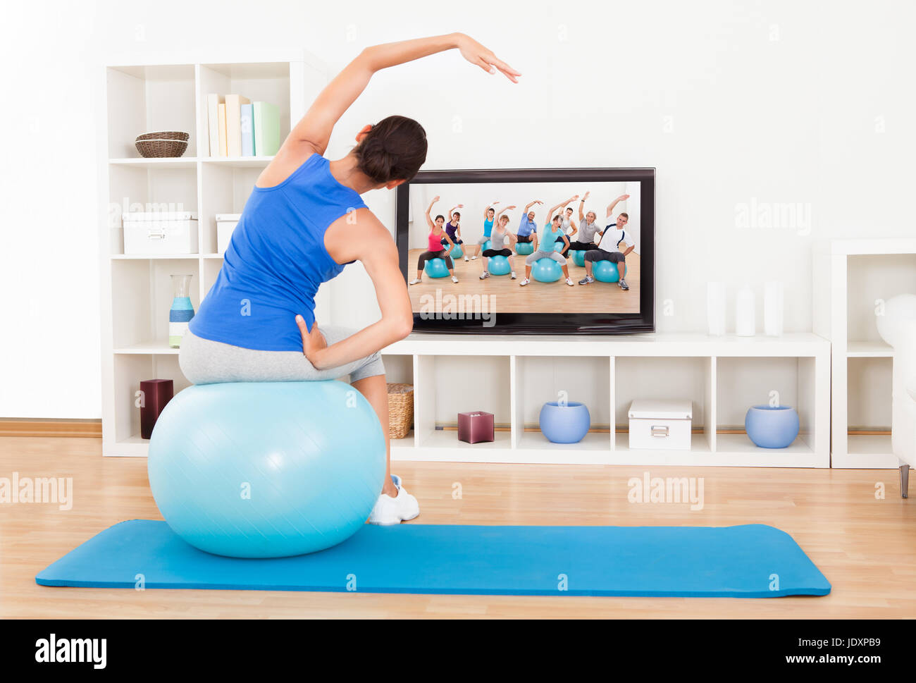 Woman working out at home watching tv hires stock photography and