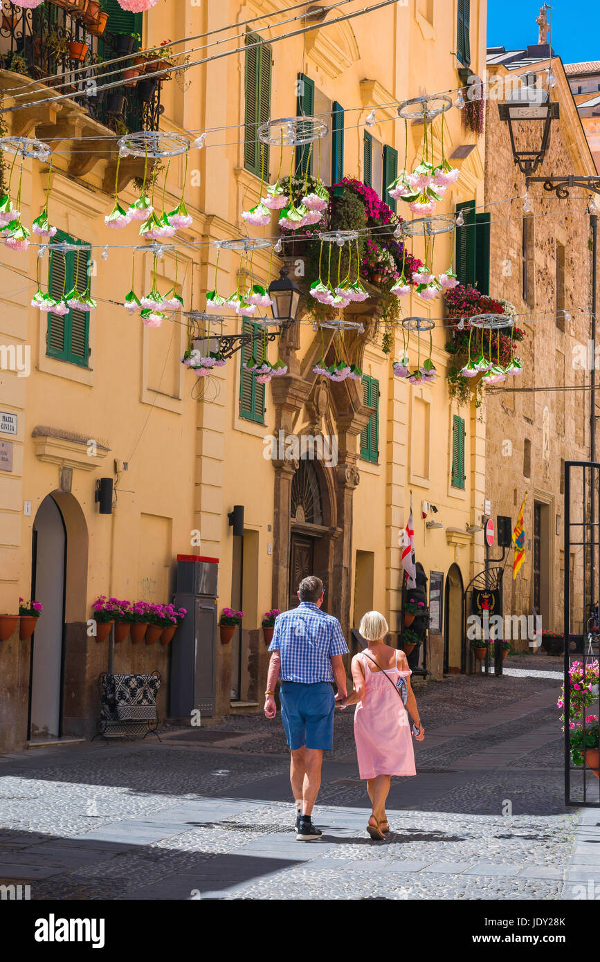 Mature couple holiday Mediterranean, a middle aged couple stroll through the old town in Alghero, northern Sardinia, Italy. Stock Photo