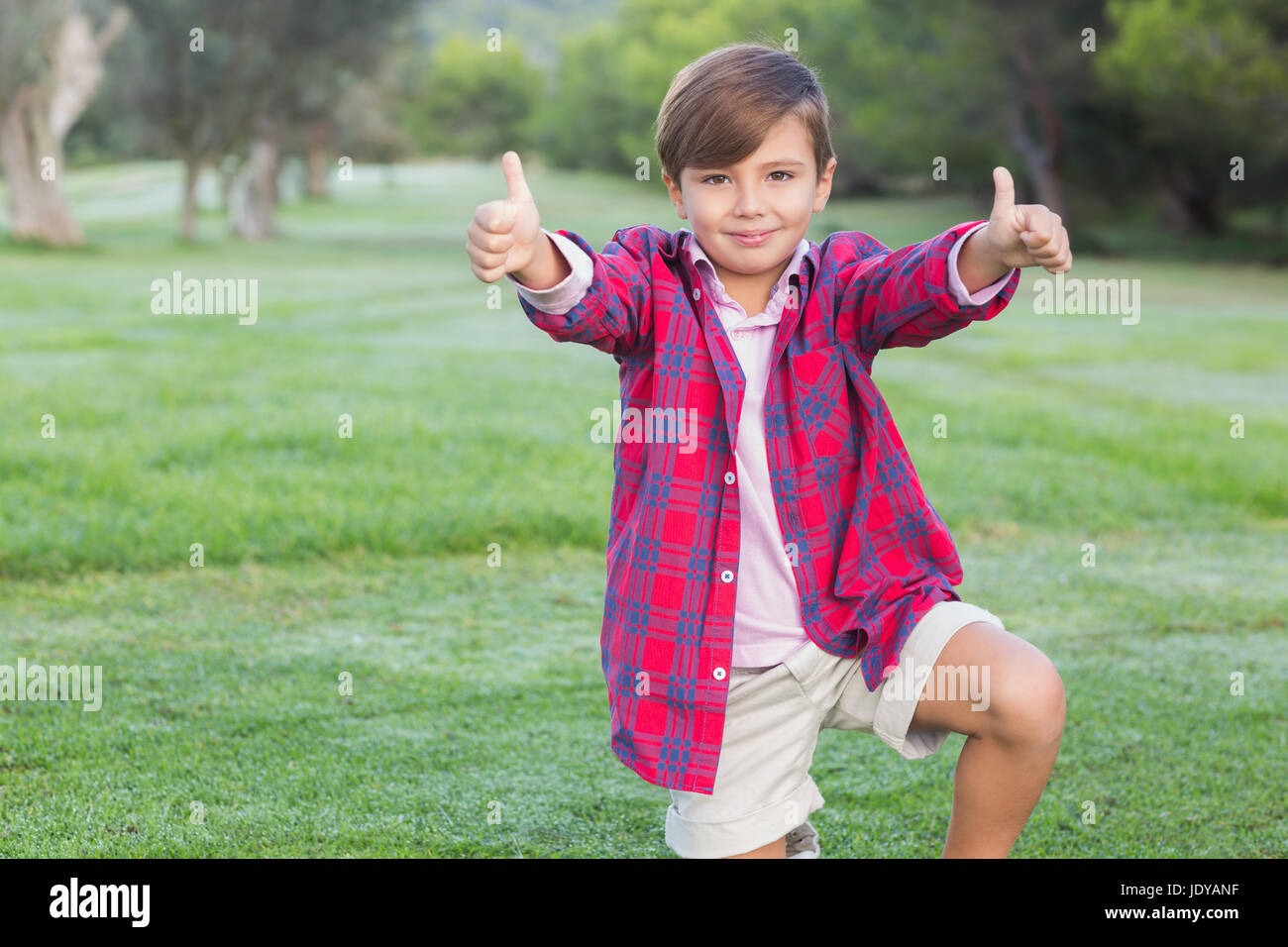 Smiling boy in park giving thumbs up Stock Photo - Alamy