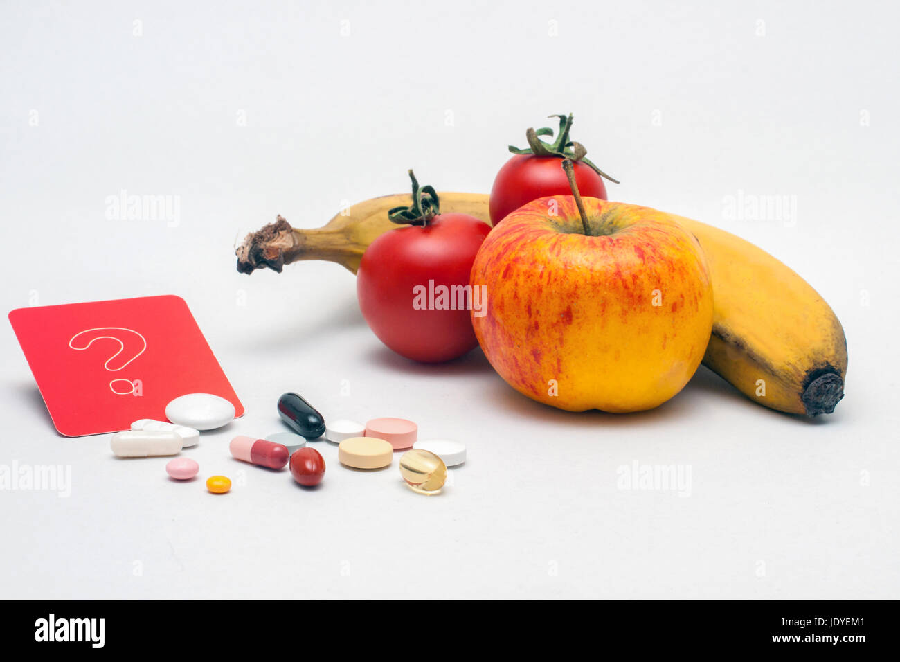 verschiedene bunte Tabletten, Apfel, Banane, Tomaten und rotes Fragezeichen-Schild, isoliert Stock Photo